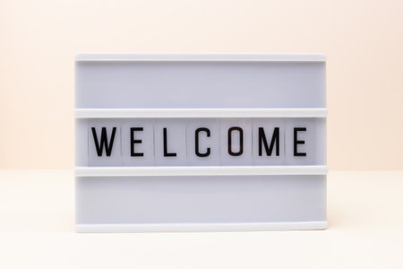 Word Welcome. Lightbox with letters in front of beige background.の写真素材