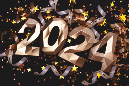 Closeup of gold colored 2024 numbers, stars confetti and ribbons on a black background. New year concept.の写真素材