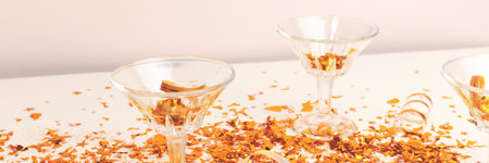 Banner with crystal glasses and golden confetti in front of beige background. Festive concept.の写真素材