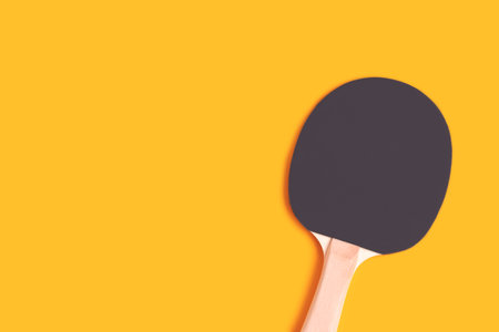 One table tennis racket on a yellow background. Place for text.