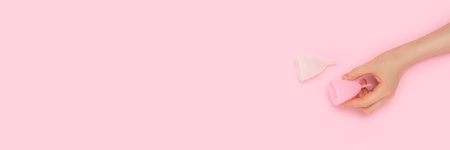 Banner with hand hold menstrual cup on a pink background.の写真素材