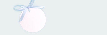 Banner with silver round blank tag with tied blue ribbon bow. Monochrome composition with place for text.の写真素材