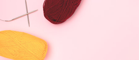 Banner with knitting needles and skeins of wool threads on a pink background.の写真素材