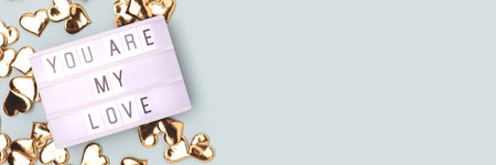 You are my love. Banner with lightbox and gold colored confetti in a heart shape on a blue background with place for text.の写真素材