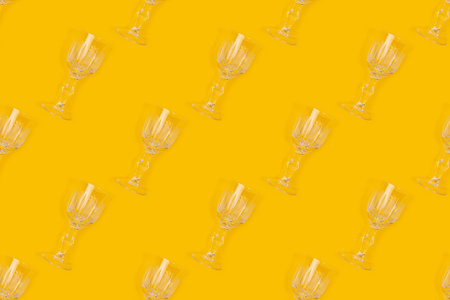 Pattern made of vintage crystal glasses on a yellow background. Creative backdrop.の写真素材