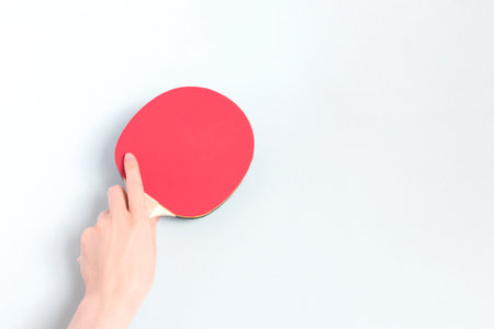 Female hand hold racket for table tennis on a blue background. Composition with place for text.の写真素材