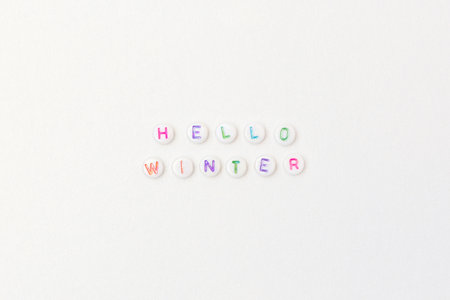 Hello winter. Quote made of white round beads with multicolored letters on a silver glittering background.の写真素材