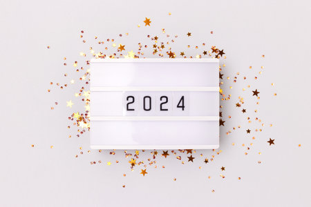 Lightbox with 2024 numbers and golden stars confetti on a gray background. New Year concept.の写真素材