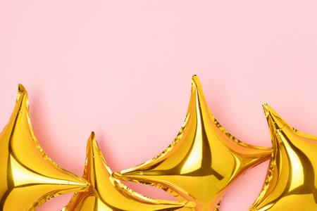 Frame made of gold colored air star balloons on a pink background. Festive concept with copy space. Selective focus.の写真素材