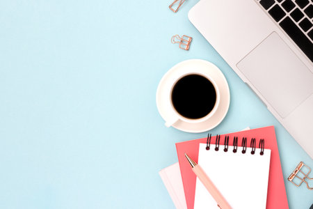Office supplies, laptop and cup of coffee on a blue background. Online education concept with copy...
