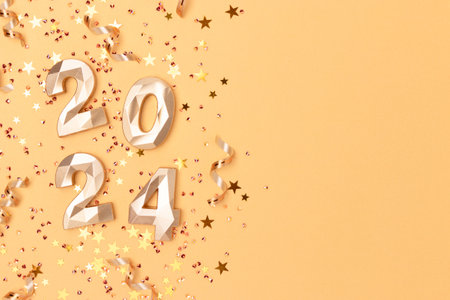2024 numbers, shiny stars confetti and ribbons on a golden background. New Year festive concept with copy space.の写真素材