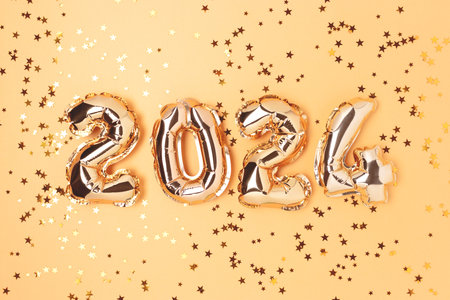 2024 gold balloons and stars confetti. Monochrome festive composition.の写真素材