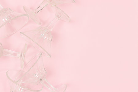 Small crystal glasses scattered on a pink background. Concept with place for text.の写真素材