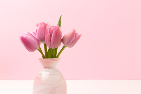 Vase with bouquet of tulip flowers in front of pink background. Composition in pastel colors.の写真素材