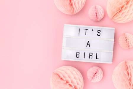 It's a girl. Lightbox with letters and tissue paper balls in a pink color. Baby shower composition with copy space.の写真素材