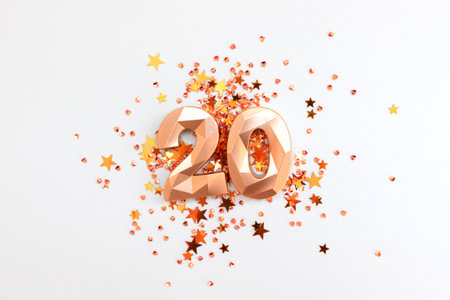 Gold colored number 20 and stars confetti on a blue pastel background. Festive composition.の写真素材