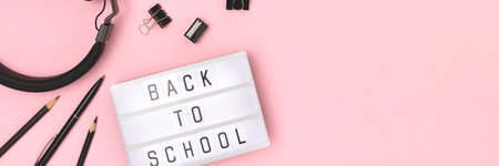 Banner with quote Back to school. Lightbox with letters, headphones and stationery on a pink background.の写真素材