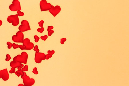 Red textile hearts confetti scattered on a gold colored background. Place for text.の写真素材