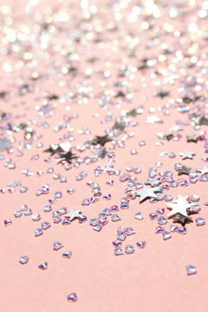 Glowing silver stars and crystals confetti on a pink background. Selective focus. Festive texture.の写真素材