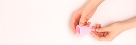 Banner with hands hold pink menstrual cup on a gray background. Zero waste period concept with place for text.の写真素材