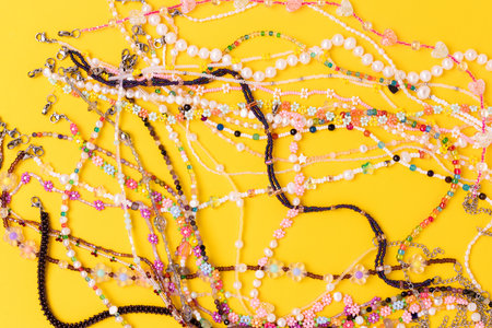 Multicolored chains of beads, pearls and natural stones scattered on a yellow background.の写真素材