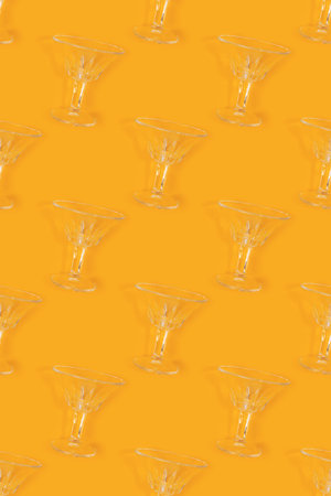 Repetitive pattern made of vintage crystal glasses on a yellow background. Creative concept.の写真素材