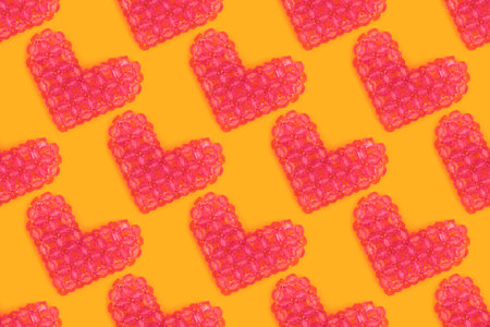 Repetitive pattern made from beaded pink hearts on a yellow background.