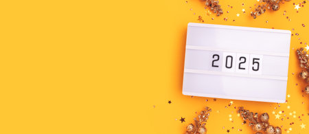 Banner with 2025 numbers, lightbox, gold colored stars confetti and decorative branches on a yellow...