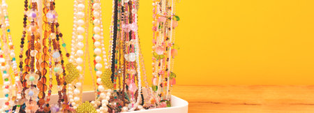 Banner with handmade chains of beads and natural stones in front of yellow background.