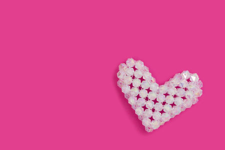 White heart figurine made from acrylic beads on a magenta background.の写真素材