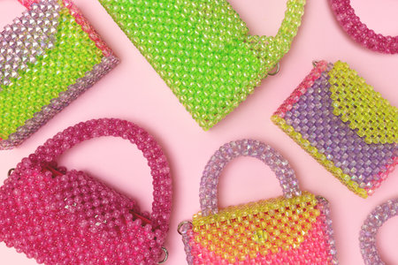 Handcrafted beaded bags scattered on a pink background. Trendy accessories.