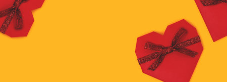 Red gift boxes in a heart shape scattered on a yellow background. Banner with place for text.の写真素材