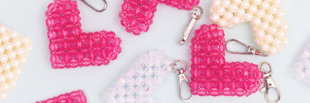 Banner with handmade keychains in a heart shape made from beads on a blue background.