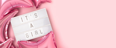 It's a girl. Banner with lightbox and foil balloons in a pink color. Baby shower composition.の写真素材