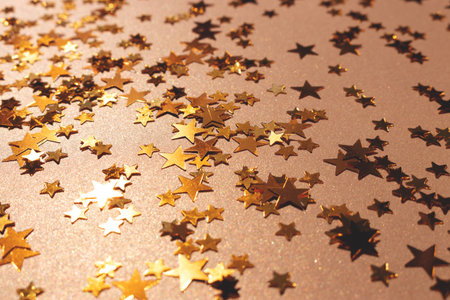 Shiny stars confetti scattered on a golden background. Selective focus.
