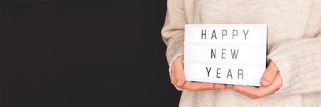 Happy New Year. Banner with hands hold lightbox in front of black background.の写真素材