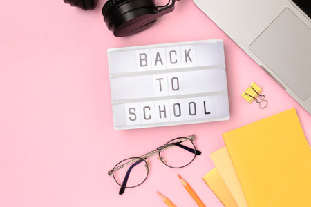 Back to school. Workspace with lightbox, eyeglasses, laptop and office supplies on a pink background. Online education concept with place for text.の写真素材