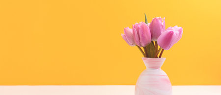 Vase with bouquet of tulip flowers in front of yellow background. Banner with copy space.
