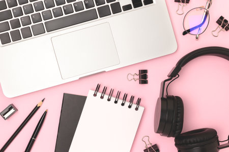 Laptop, headphones and office supplies on a pink background. Business concept.の写真素材
