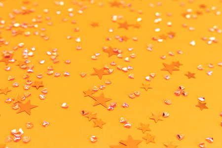 Shimmer golden stars and crystals confetti on a yellow background. Festive texture. Selective focus.の写真素材