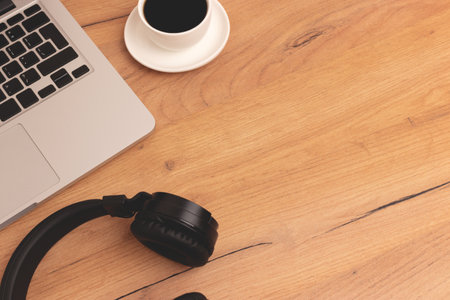 Laptop, cup of coffee and headphones on a wooden desk. Place for text.の写真素材