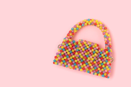 Handmade bag made from multicolored beads on a pink background.の写真素材