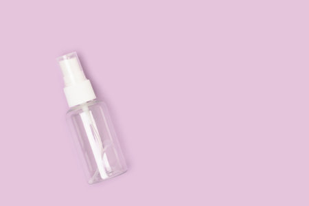 Empty transparent spray bottle on a purple background. Place for text.の写真素材