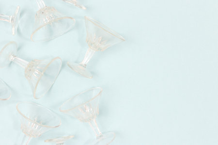 Small crystal glasses scattered on a blue background. Place for text.の写真素材