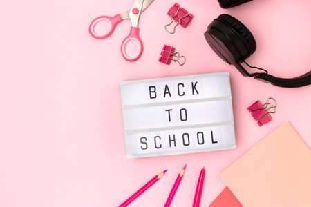 Back to school. Lightbox with letters, headphones and stationery on a pink background. Place for your design.の写真素材