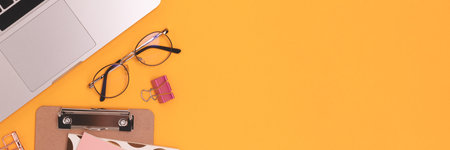 Banner with laptop, eyeglasses and stationery on a yellow background.