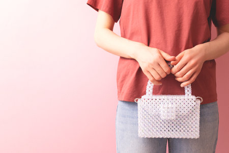 Unrecognizable woman with a handcraft bag made from shiny acrylic beads in her hands in front of...