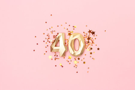 Golden number fourty and stars confetti on a pink background. Festive creative concept.の写真素材