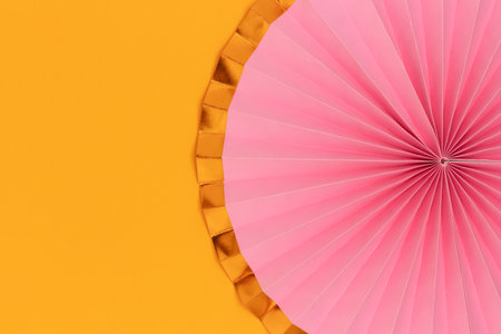 Pink paper fan on a yellow background. Festive concept with copy space.の写真素材