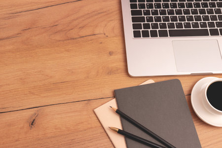 Business concept with place for text. Laptop, cup of coffee and stationery on a wooden desk.